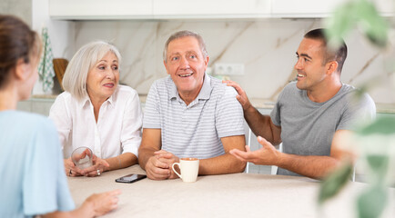 Obraz premium Family (mother, father, son, daughter) having fun talking in kitchen with each other