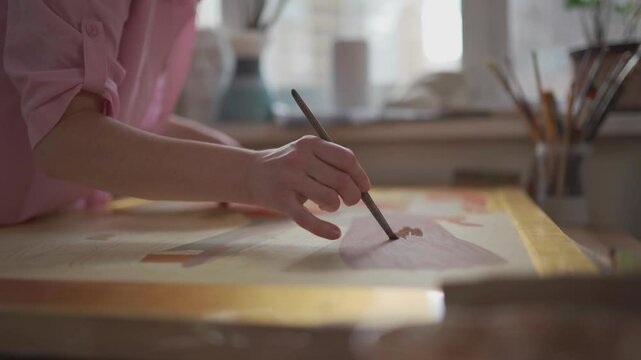 Hands a woman artist works with a brush and paint in the studio. Creativity Concept. People, leisure and hobby. Oil painting. Woman painting on canvas in an art workshop. Artist at the workplace. 