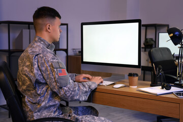 Young male soldier working with computer in headquarters at night