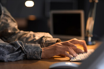 Female soldier working with computer in headquarters at night, closeup
