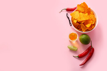 Bowl of tasty nachos, tequila and chili peppers on pink background. El Dia de Muertos