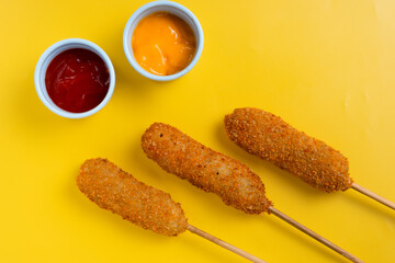 Korean corndog with a crispy golden crust, isolated on a vibrant yellow background. Perfect for recipe, article, catalogue, commercial, or any cooking content.