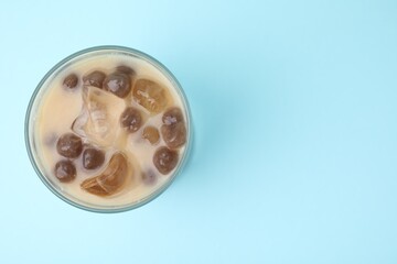 Tasty milk bubble tea in glass on light blue background, top view. Space for text