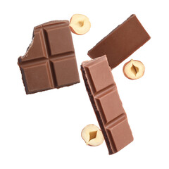 Pieces of tasty chocolate and hazelnuts in air on white background