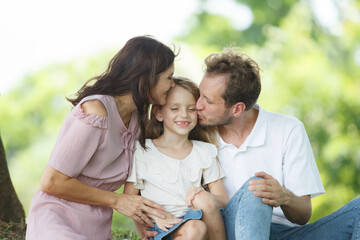 Obraz premium Happy family relaxing together at the park, caucasian family with father, mother, and children walking at the park.
