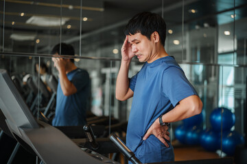 man with headache and low back pain on treadmill at fitness gym exercise