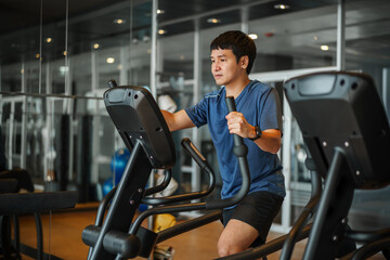 man doing exercise on an elliptical cross trainer in sport fitness gym