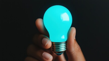 A person is holding a light bulb that is glowing blue