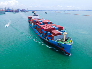 the aerial perspective of a cargo ship being loaded and unloaded at a bustling seaport and sailing...