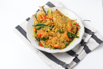 Close up view of Indonesian style spicy fish with yellow sauce, on a white plate