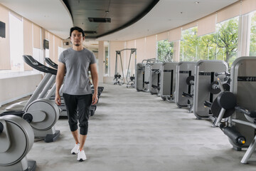 Asian Thai man walking in gym after done workout exercise, happy and healthy strong concept.