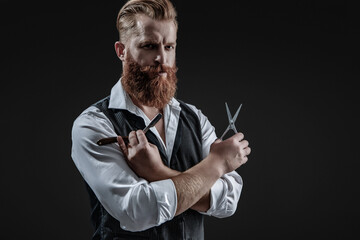 Man beard haircut by hairdresser at barbershop. Handsome barber using retro blade and scissors while cutting hair. Modern barbershop haircut. Bearded hipster barber isolated on black