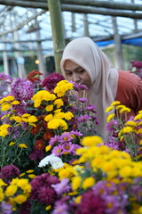 Fototapeta premium A Muslim woman is enjoying flowers in the garden