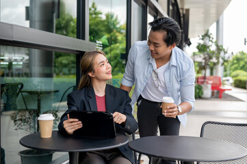 Two positive Asian colleagues, a female and a male, are having an informal meeting at a coffee shop.
