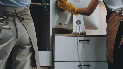 Woman in yellow gloves cleaning table with rag and bottle of cleaning solution