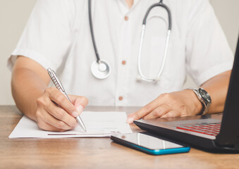 Doctor writing medical notes on patient records.