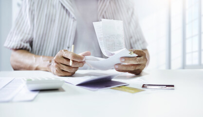 Asian man holding many receipt calculate monthly expenses after use credit card for business and shopping and must be pay back soon
