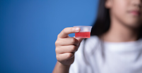 Young girl holding cough syrup with medicine. Healthcare concept