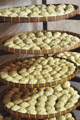 Raw steamed buns arranged in rows on a bamboo tray.