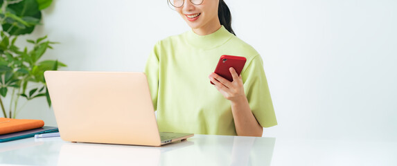 部屋でノートパソコンとスマホを使う女性