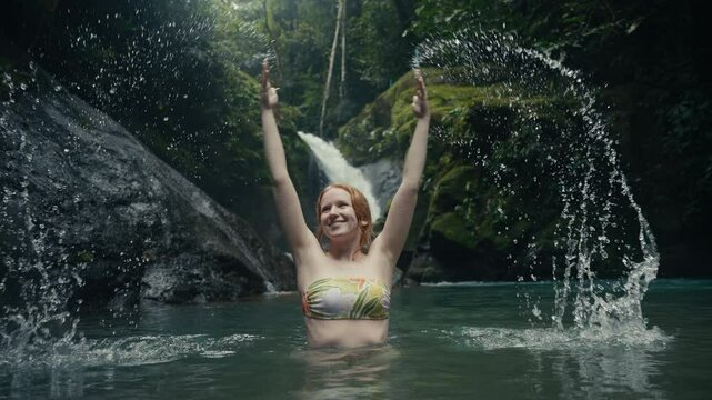 Young woman enjoying a tropical rainforest waterfall in the jungle 