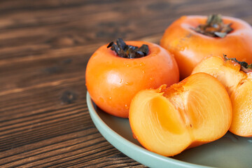 Fresh persimmon fruit on wooden background. Healthy food concept.