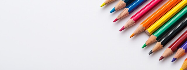 Fototapeta premium A line of color pencils aligned atop a white tabletop, spaces reserved for inscriptions