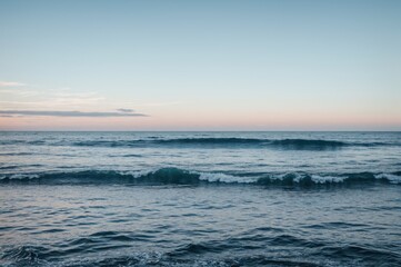 Obraz premium Calm ocean with gentle ripples under a serene pastel sky 