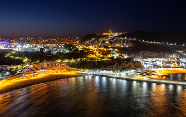 Fototapeta premium Picturesque night view of Al Hoceima city and modern hotel buildings on the shore of the Mediterranean Sea bay