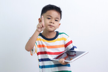 smiling little boy stiiting and holding a tablet.