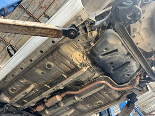 Underneath vehicle, showcasing exhaust system, chassis, and suspension components. image captures intricate details of automotive engineering.