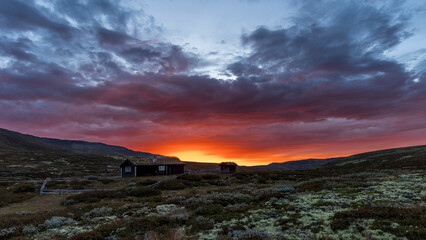Sunrise over a typical wooden house under a cloudy sky, Dovrefjell region, Norway