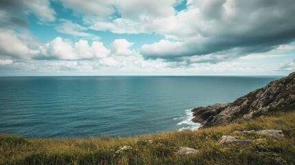 Coastal hillside overlooking the vast blue ocean, with the sky filled with soft clouds and plenty of copy space.
