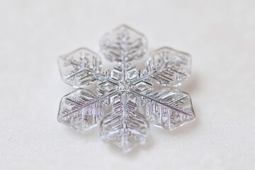 Fototapeta premium A delicate, transparent snowflake ornament with intricate details resting on a soft surface, capturing the beauty of winter.