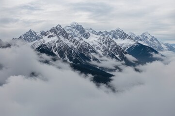 Obraz premium Snow-capped peaks of majestic mountains rising above swirling clouds in tranquil nature