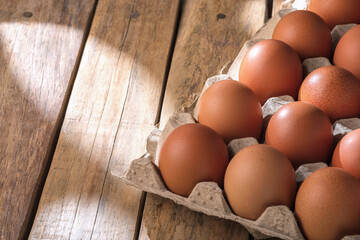 Fresh chicken eggs in cardboard boxes arranged on wooden background with copy space for text.