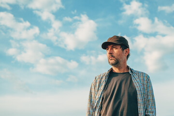 Portrait of male farm worker in field wearing trucker's hat against sunny summer sky