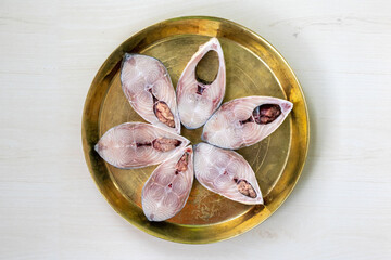 Slices of fresh raw hilsa fish on brass plate, ready for cooking. The famous ilish fish of the...