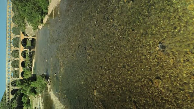 Vertical drone flight over river with swimming kids in front of Aqueduc de Roquefavour in France. Wide shot.