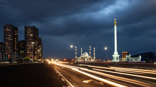 Kazakhstan Independence Monument with the magical bird Samruk on top and the Khazret-Sultan Mosque in Astana on a summer evening