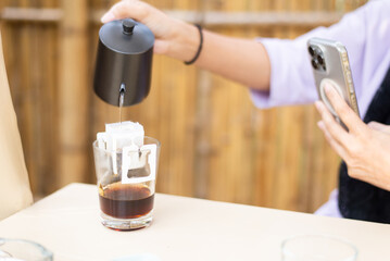 Hand pouring hot water from teapot into tea bag