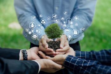 Businessman holding green plants with icons representing renewable energy, sustainability and...