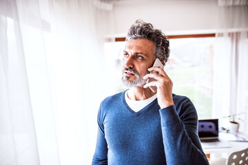 Homeoffice for handsome man. Man working in his office in home, making phone call. Telecommuting.