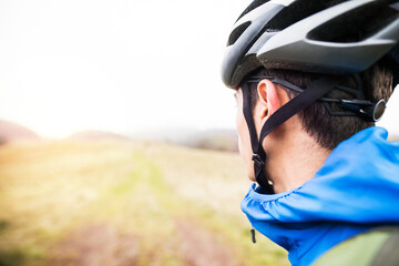 Close up of man with bike helmet in the middle of beautiful nature, early autumn morning. Concept of healthy lifestyle.