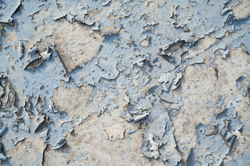 a concrete wall with old cracked flaking paint. Weathered rough painted surface with patterns of cracks and peeling.