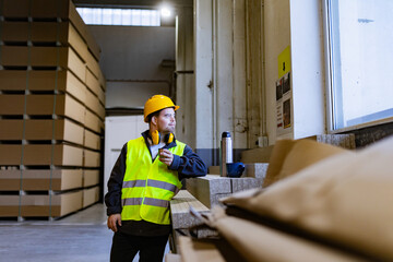 Worker with Down syndrome having break in factory, warehouse, drinking coffee from thermos. Concept of workers with disabilities, support in workplace.