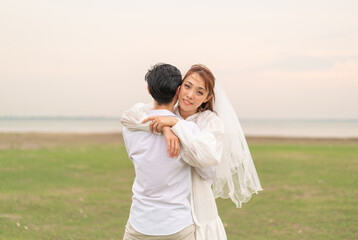 Fototapeta premium Happy young Asian couple in bride and groom clothing