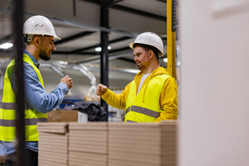 Young man with Down syndrome working in modern factory, fist bump with colleague. Concept of workers with disabilities, support in workplace.