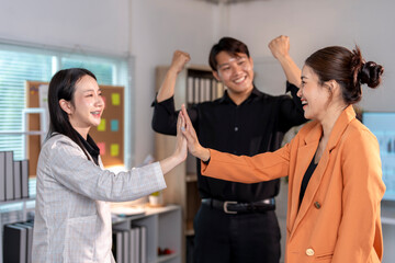 Fototapeta premium Happy business team giving high five together in office