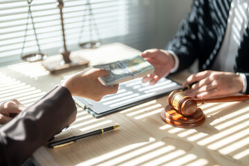 Businesswoman bribing lawyer with money at desk